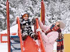 Child coming down a slide in the snow.