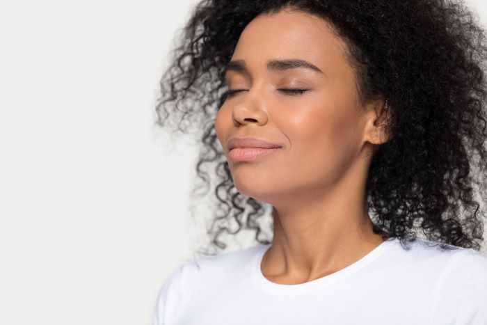 Woman sitting back and taking a deep breath to relax.