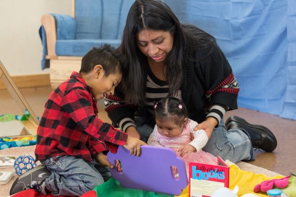 Madre e hijo ayudando a su hija a jugar con juguetes.