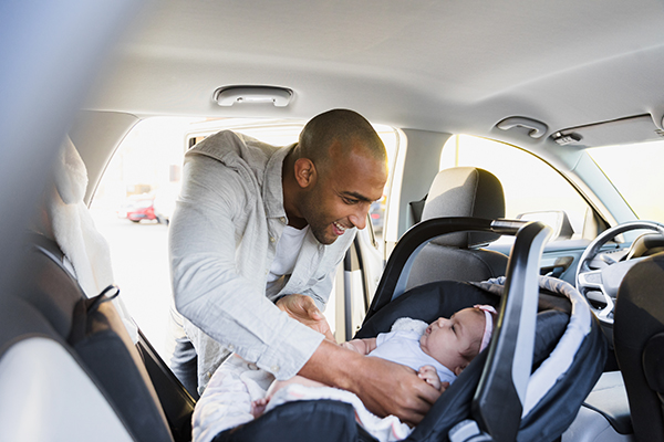 Man securing a child in her car seat.