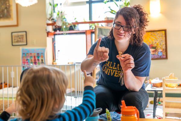 A teacher and child using American Sign Language to communicate with one another.