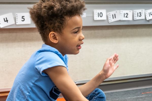 Young boy sitting on the floor of a classroom.