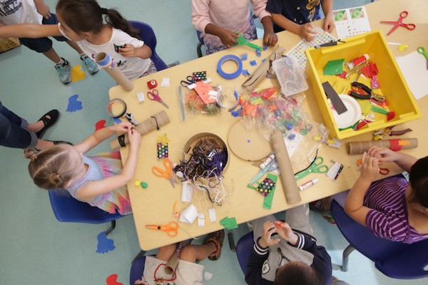 View from above a table of several children working on art projects.