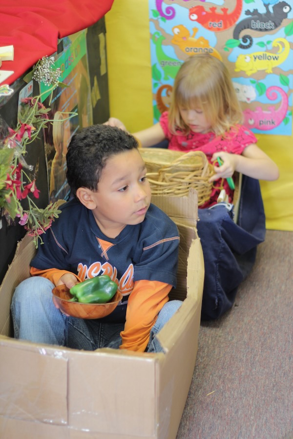 Young boy sitting inside a box as if it were a car.