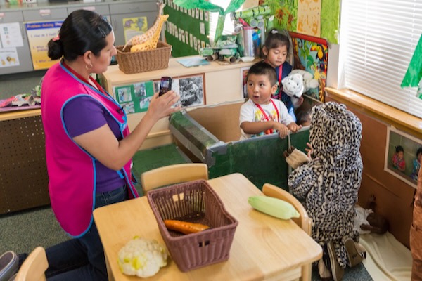 Children and teacher playing with vegetables.