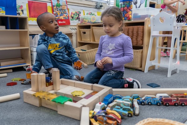 A boy and girl playing with large wooden blocks.