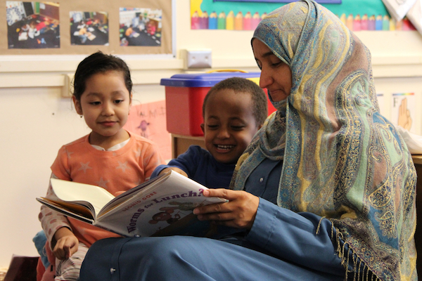 Teacher reading a book to two children.