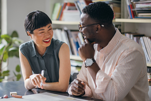 Man and woman talking while seated at a desk.