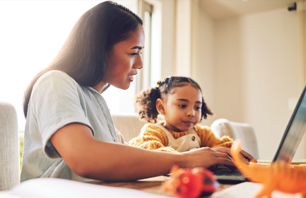 Mother and daughter sitting together and looking at a computer screen.