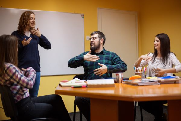 A group of people being shown a gesture with thier hands.
