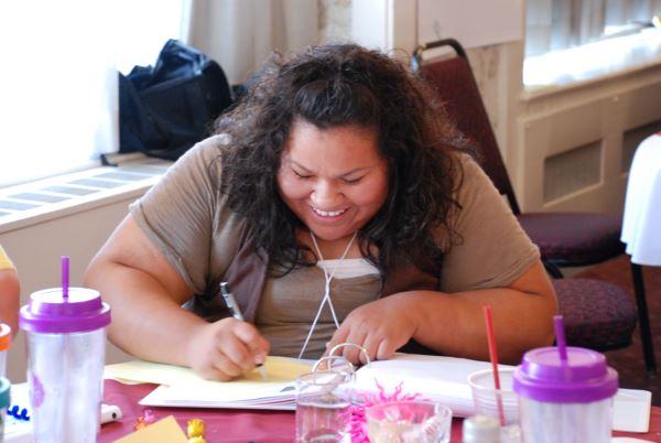 A smiling woman taking notes.
