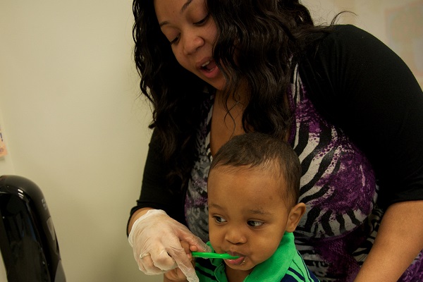 Teacher helping a child to brush his teeth.