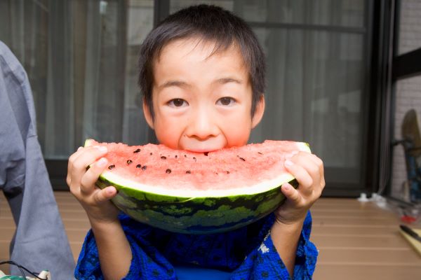 Child eating a large slice of watermellon.