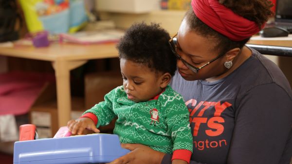 An adult holds an infant on their lap.