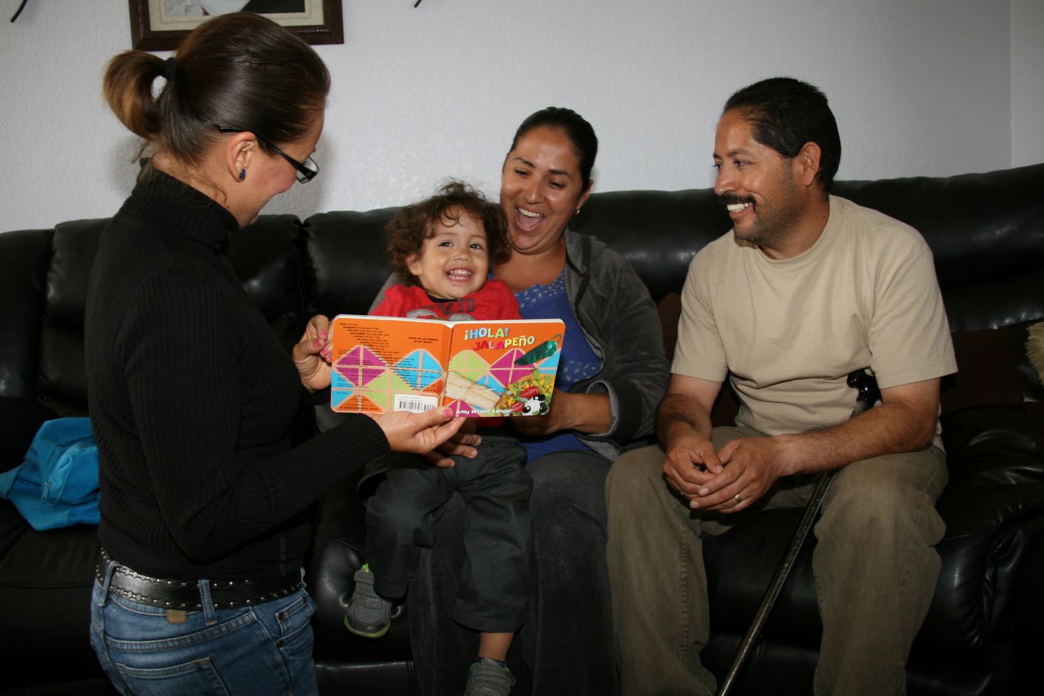 Home visitor with parents and child looking at a book.